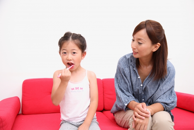 歯磨きしている子どもを見守る親